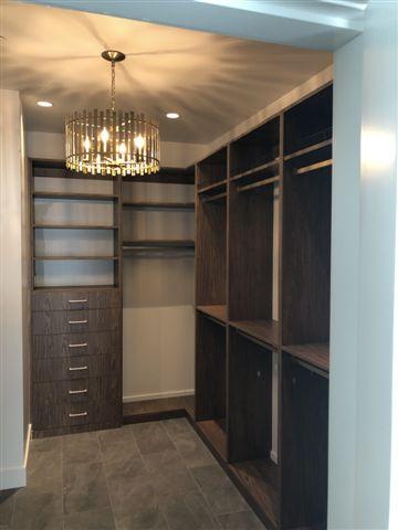 Modern walk-in closet with chandelier lighting.