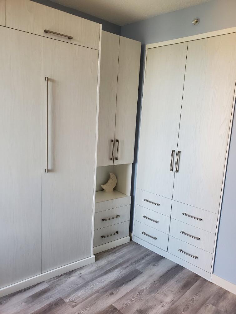 White wardrobes with drawers in corner room.