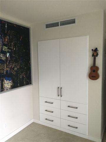 White cabinet with ukulele on wall.