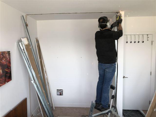 Person working on ceiling renovation with tools.